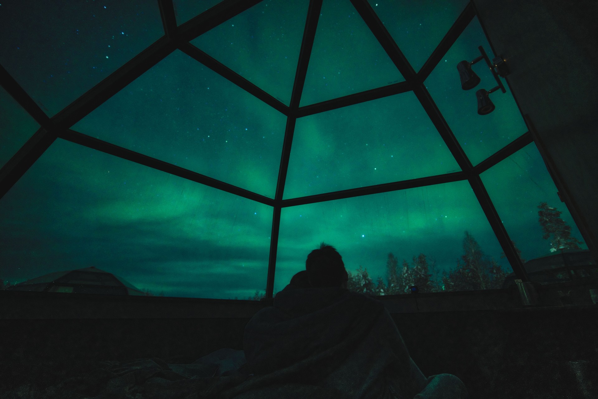 A couple enjoy view of Aurora Borealis and stars in glass igloo in Lapland, Rovaniemi, Finland A couple enjoy view of Aurora Borealis and stars in glass igloo in Lapland, Rovaniemi, Finland